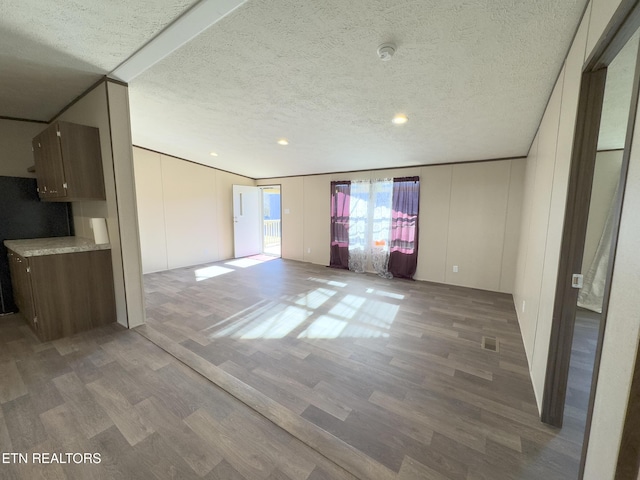 unfurnished living room featuring visible vents, a textured ceiling, and wood finished floors