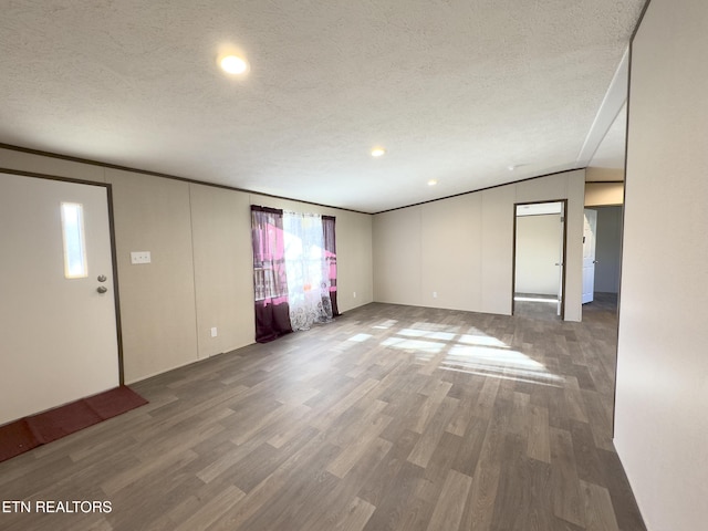 unfurnished living room featuring a textured ceiling, wood finished floors, and crown molding