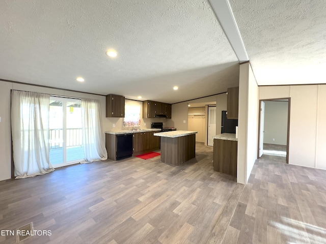 kitchen with black appliances, a kitchen island, wood finished floors, dark brown cabinetry, and light countertops