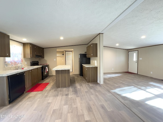 kitchen featuring light wood finished floors, a kitchen island, a sink, black appliances, and light countertops