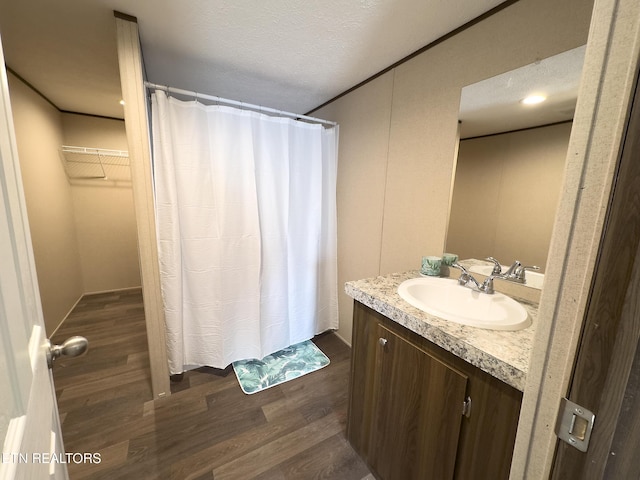 bathroom featuring vanity, curtained shower, wood finished floors, and a textured ceiling