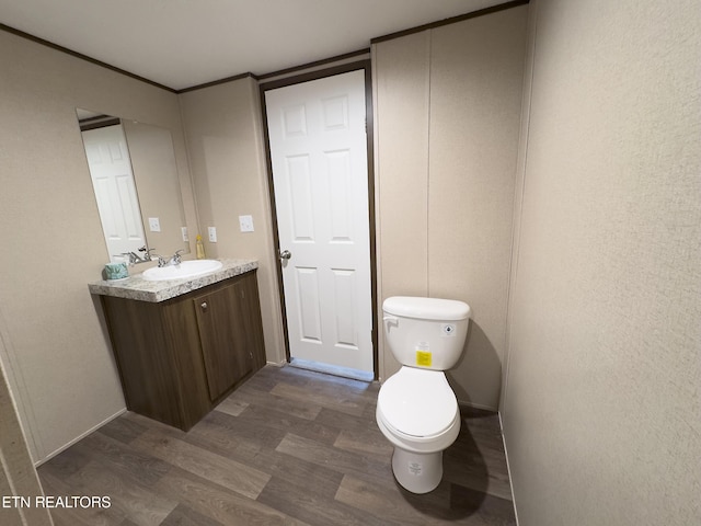 half bathroom with toilet, vanity, and wood finished floors