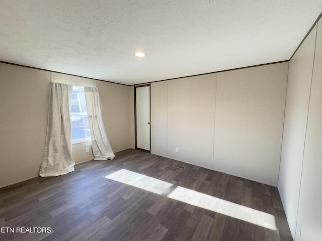 unfurnished bedroom featuring a textured ceiling, wood finished floors, and ornamental molding