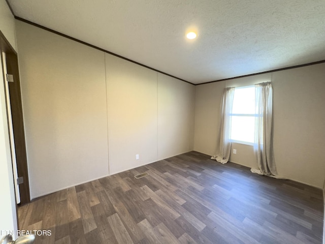 empty room featuring dark wood finished floors, a textured ceiling, and ornamental molding