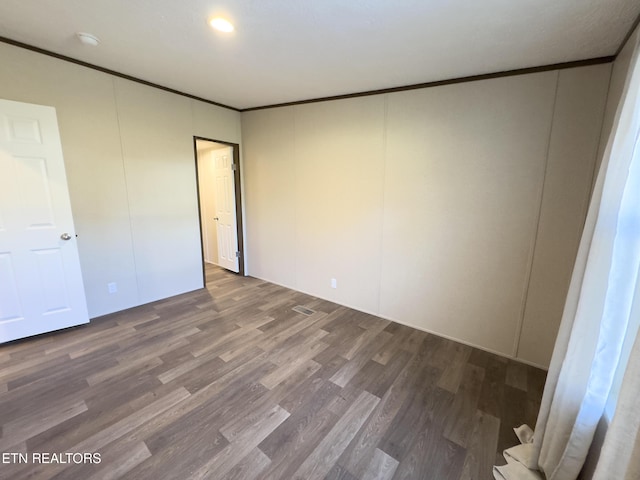 empty room featuring wood finished floors and crown molding