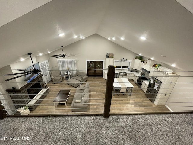 interior space with dark colored carpet, vaulted ceiling, and ceiling fan