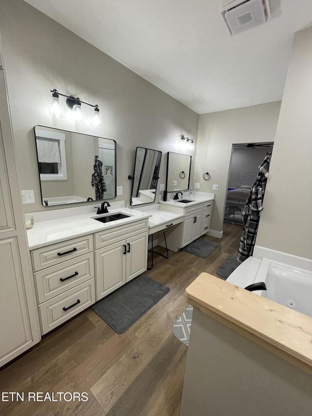 bathroom with wood-type flooring, a bathing tub, and vanity