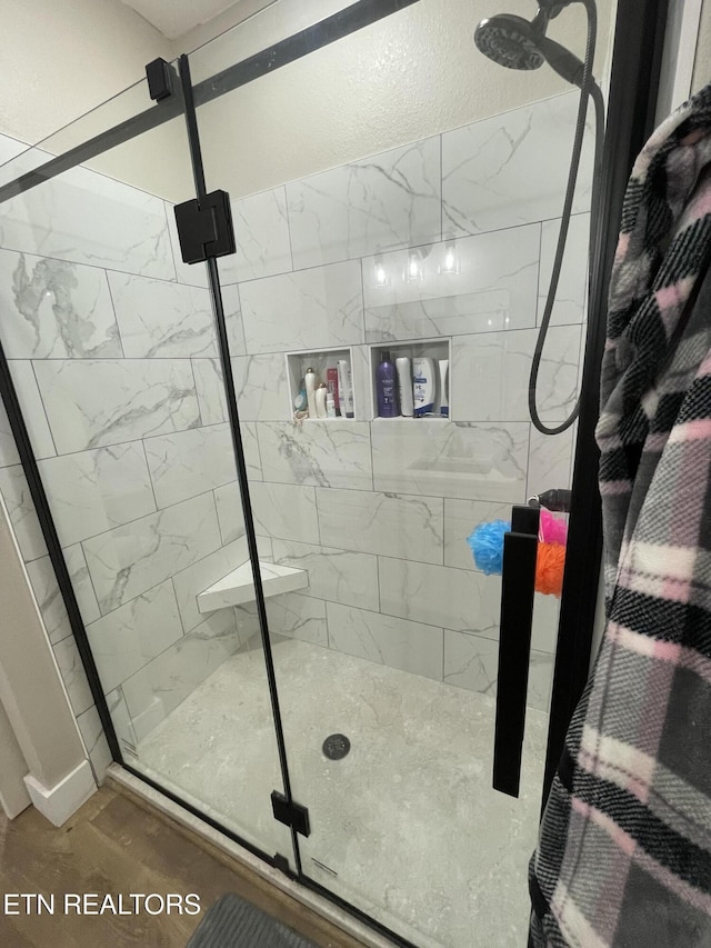 bathroom with a shower with shower door and hardwood / wood-style floors