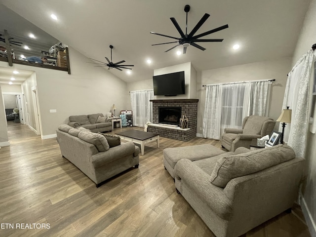 living room featuring ceiling fan, wood-type flooring, a fireplace, and vaulted ceiling