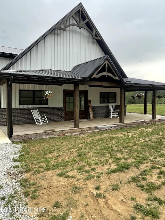 136 Falling Leaf Rd, Jamestown, TN 38556 - view of front of home featuring brick siding, board and batten siding, a front yard, metal roof, and covered porch