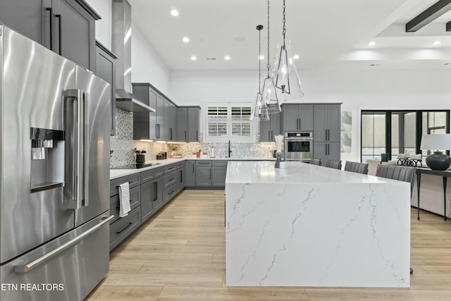 kitchen with high end refrigerator, a center island, decorative light fixtures, light stone counters, and gray cabinets