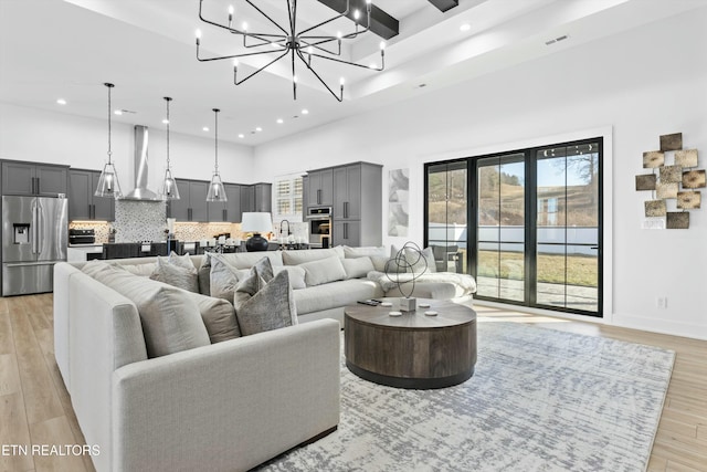 living room with sink, light hardwood / wood-style flooring, and a towering ceiling