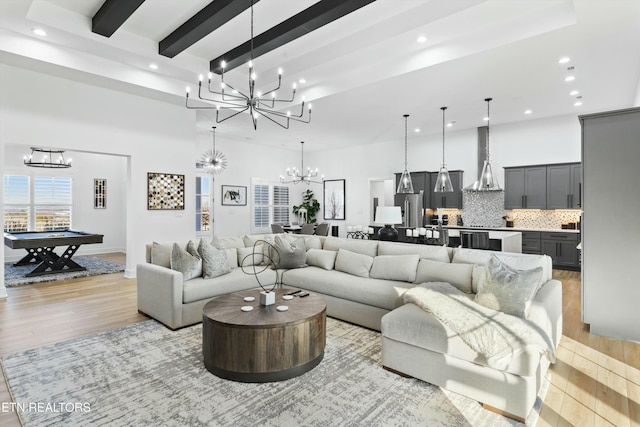 living room with light hardwood / wood-style floors, pool table, beamed ceiling, and a notable chandelier