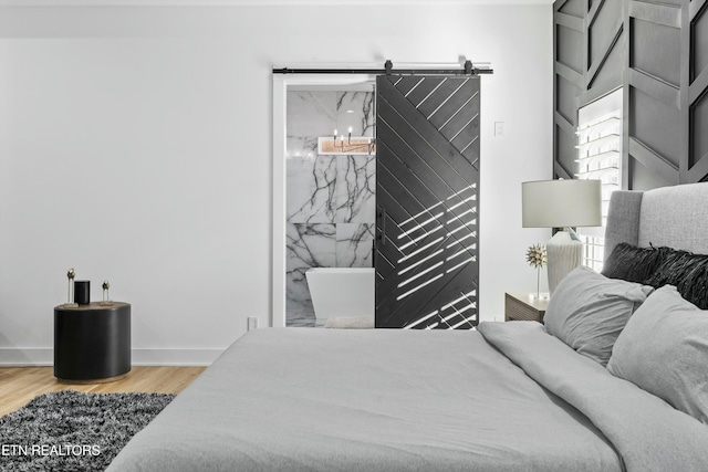 bedroom with hardwood / wood-style flooring and a barn door