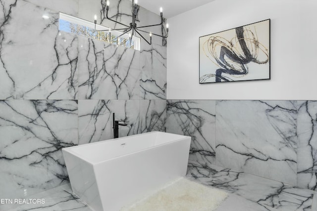 bathroom with a tub to relax in and a notable chandelier