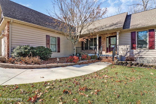 ranch-style home featuring brick siding, crawl space, a shingled roof, and a front lawn