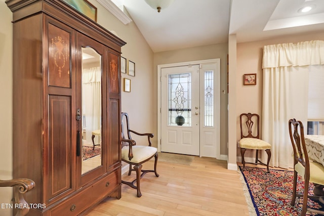 entrance foyer featuring light wood-type flooring, lofted ceiling, and baseboards