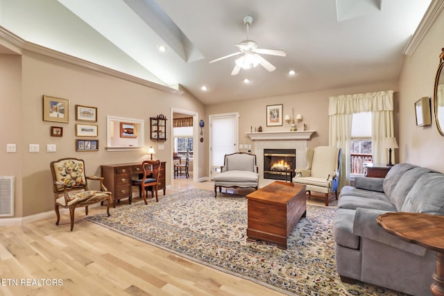 living room with lofted ceiling, visible vents, a tiled fireplace, and light wood-style flooring