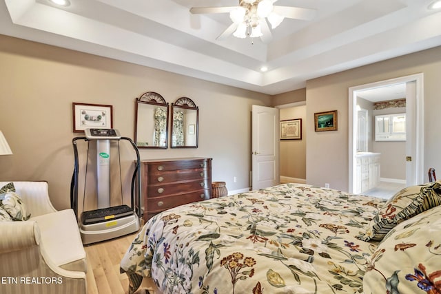 bedroom with light wood-style floors, baseboards, a raised ceiling, and recessed lighting