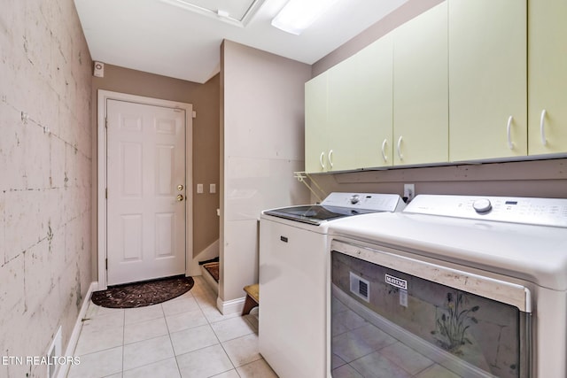 laundry room featuring washing machine and dryer, cabinet space, baseboards, and light tile patterned floors