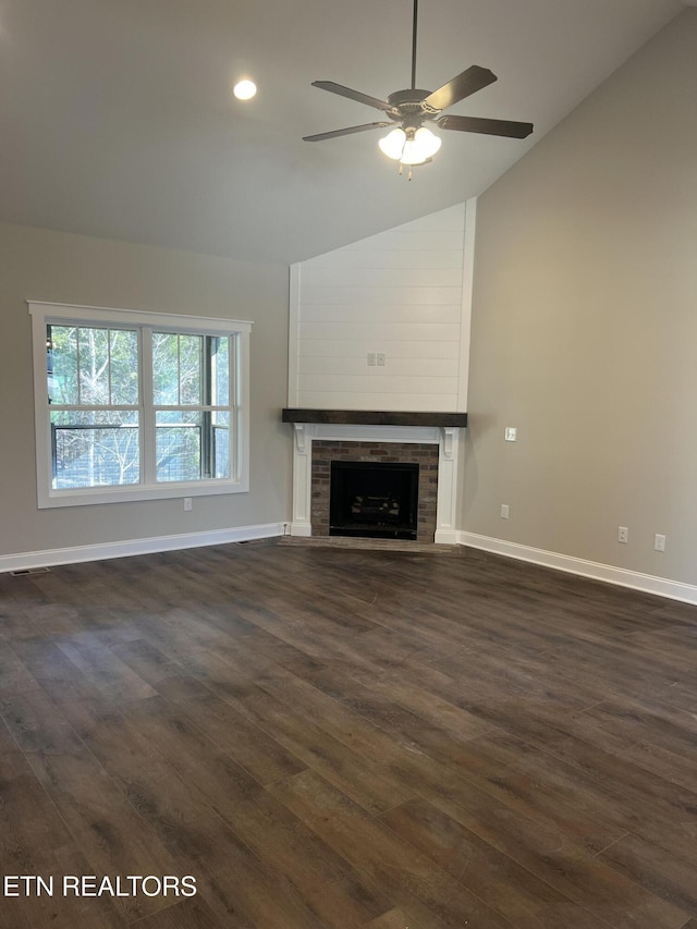 unfurnished living room with a large fireplace, ceiling fan, dark wood-type flooring, and lofted ceiling