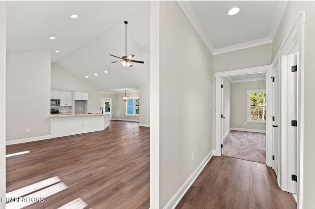 corridor with high vaulted ceiling, wood-type flooring, a chandelier, and ornamental molding