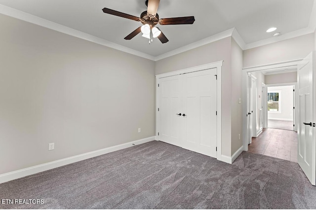 unfurnished bedroom featuring crown molding, dark colored carpet, ceiling fan, and a closet