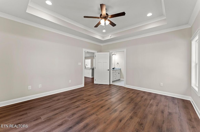 unfurnished bedroom featuring crown molding, a tray ceiling, and dark hardwood / wood-style floors