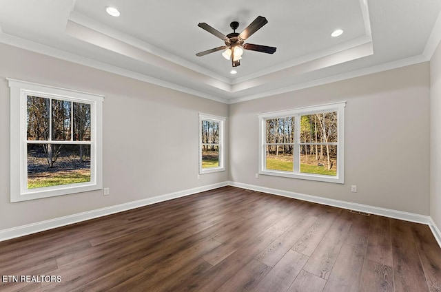 unfurnished room featuring a tray ceiling, ornamental molding, dark wood-type flooring, and ceiling fan