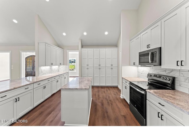 kitchen with a center island, white cabinetry, stainless steel appliances, and light stone counters