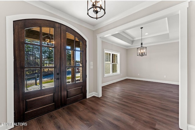 entrance foyer with a tray ceiling, dark wood-type flooring, a chandelier, and french doors