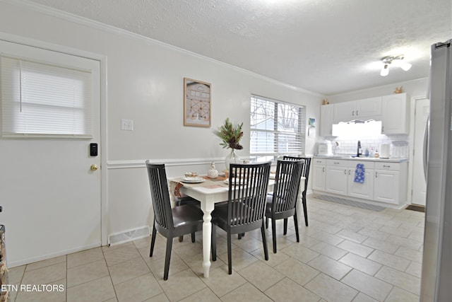 dining space with ornamental molding, sink, and a textured ceiling