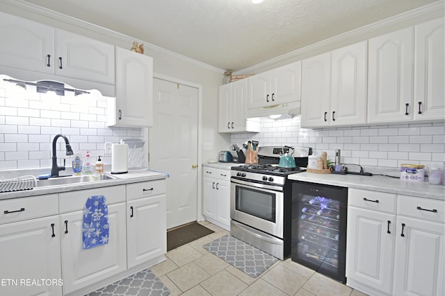 kitchen featuring white cabinetry, stainless steel range with gas cooktop, and beverage cooler