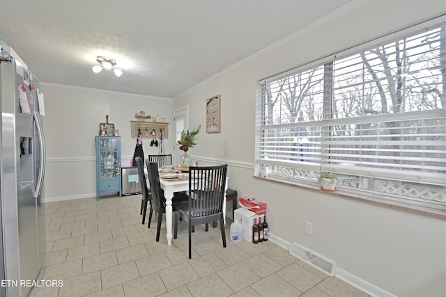 dining space with light tile patterned floors, ornamental molding, and a textured ceiling