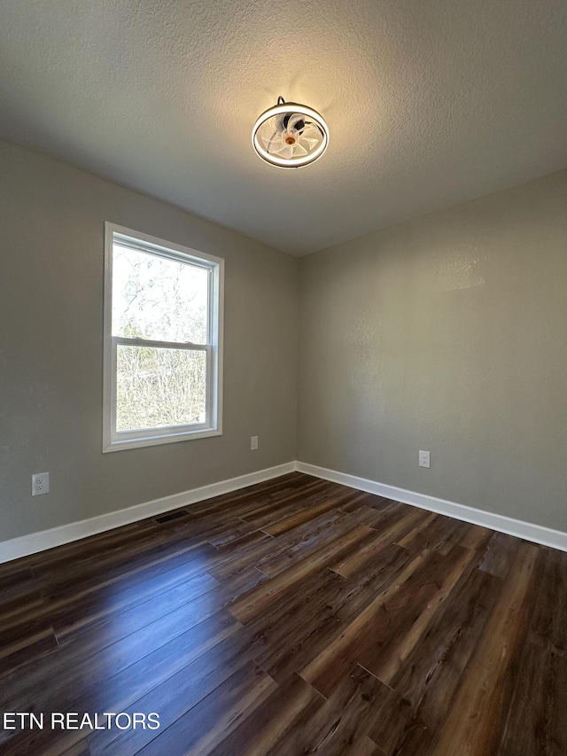 unfurnished room featuring a textured ceiling and dark hardwood / wood-style flooring