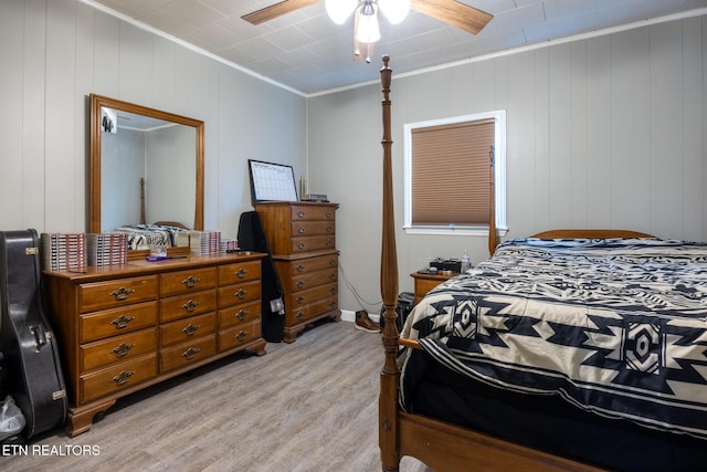 bedroom with ceiling fan, ornamental molding, wooden walls, and light hardwood / wood-style flooring