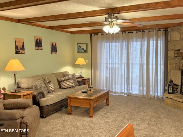 carpeted living room with beam ceiling, a stone fireplace, and ceiling fan