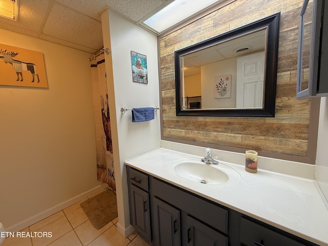 bathroom with tile patterned flooring, vanity, and a paneled ceiling