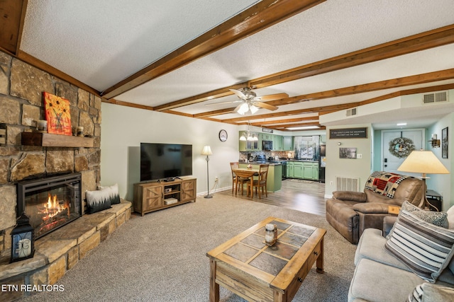 221 Woodland Rd Unit 210, Gatlinburg, TN 37738 - living room with light carpet, a ceiling fan, a stone fireplace, baseboards, and beam ceiling