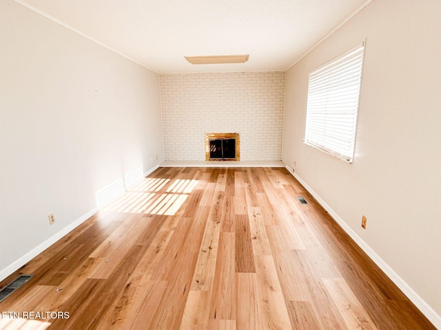 unfurnished living room featuring wood-type flooring, ornamental molding, and a fireplace