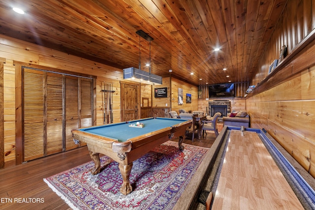 recreation room with wood-type flooring, billiards, a stone fireplace, wood ceiling, and wood walls