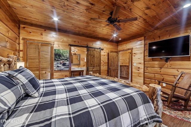 bedroom featuring wood walls, hardwood / wood-style flooring, a closet, and a barn door