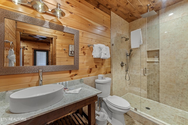 bathroom featuring vanity, toilet, wood walls, a shower with shower door, and wooden ceiling