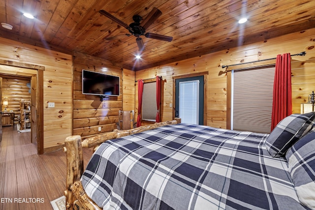 bedroom with hardwood / wood-style floors, rustic walls, wood walls, ceiling fan, and wooden ceiling