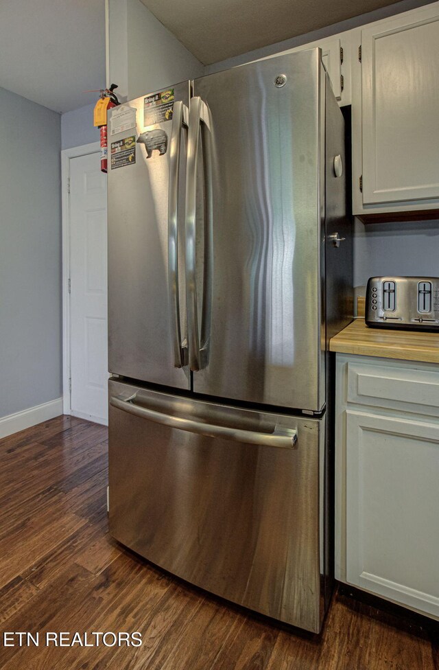 kitchen with white cabinets, dark wood-type flooring, and stainless steel refrigerator