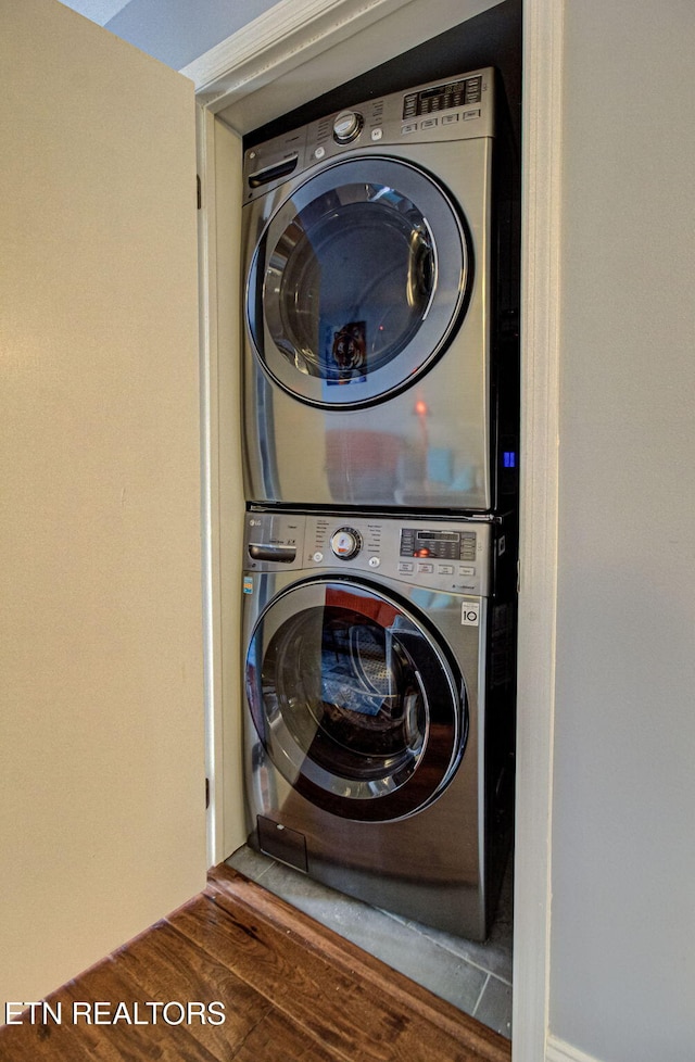 washroom featuring hardwood / wood-style flooring and stacked washer / dryer