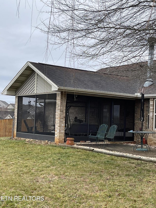 rear view of house featuring a yard and a sunroom