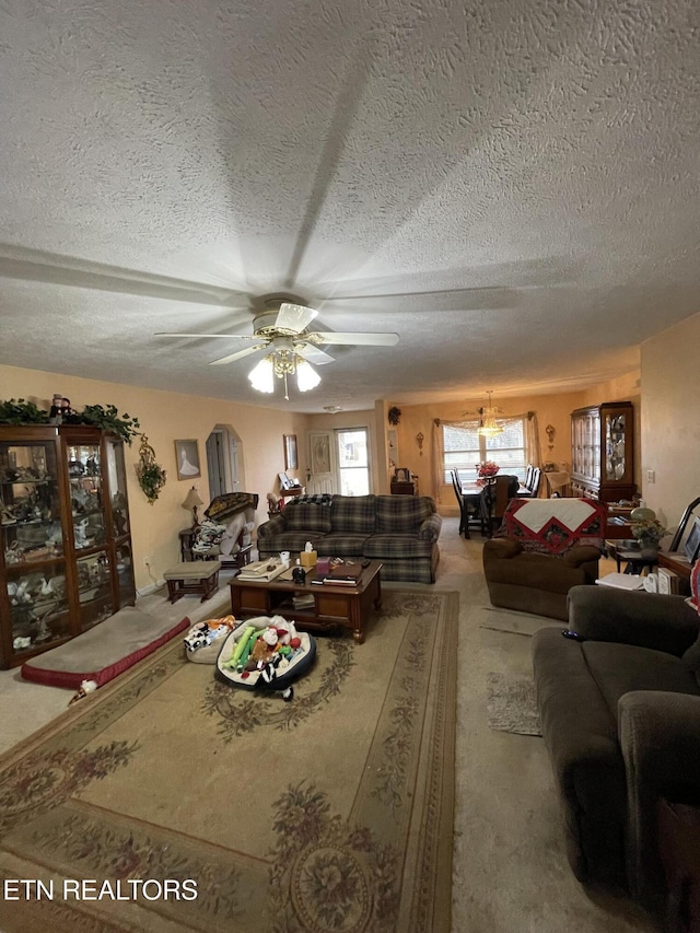 carpeted living room with ceiling fan and a textured ceiling