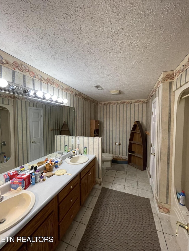 bathroom with a shower, tile patterned flooring, vanity, toilet, and a textured ceiling