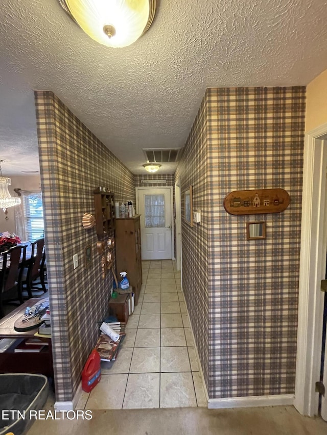 hall with a textured ceiling and light tile patterned floors